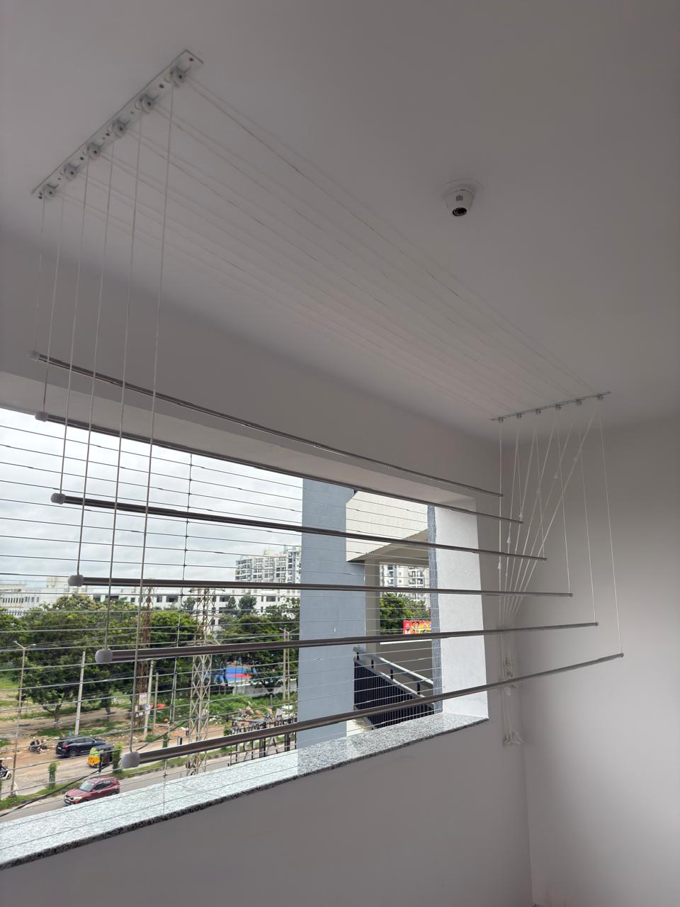 Ceiling cloth hanger with adjustable stainless steel rods installed on a Chennai balcony
