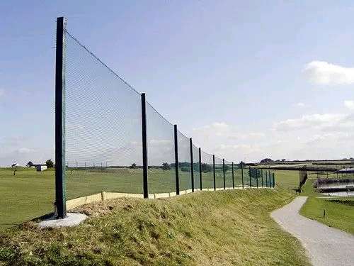 Tall golf boundary net on galvanised poles along a golf course fairway, supplied by YPL Safety Nets