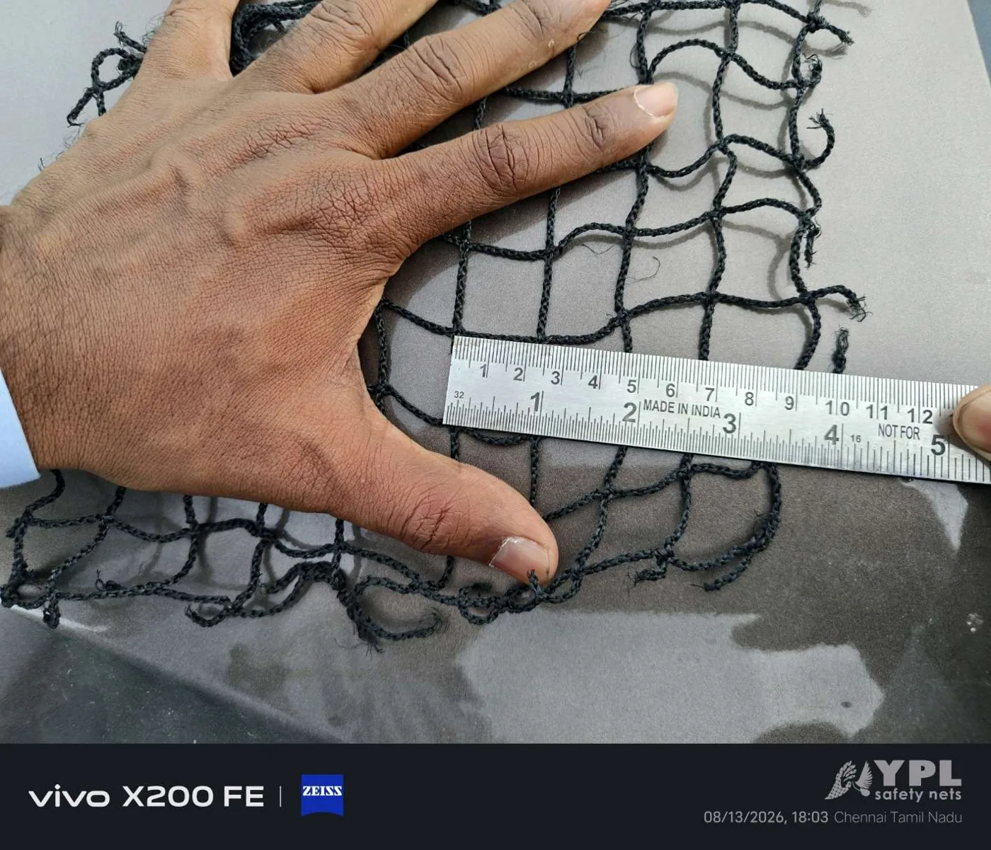 Black 2.5 mm braided safety net mesh measured by hand for construction site fall protection nets