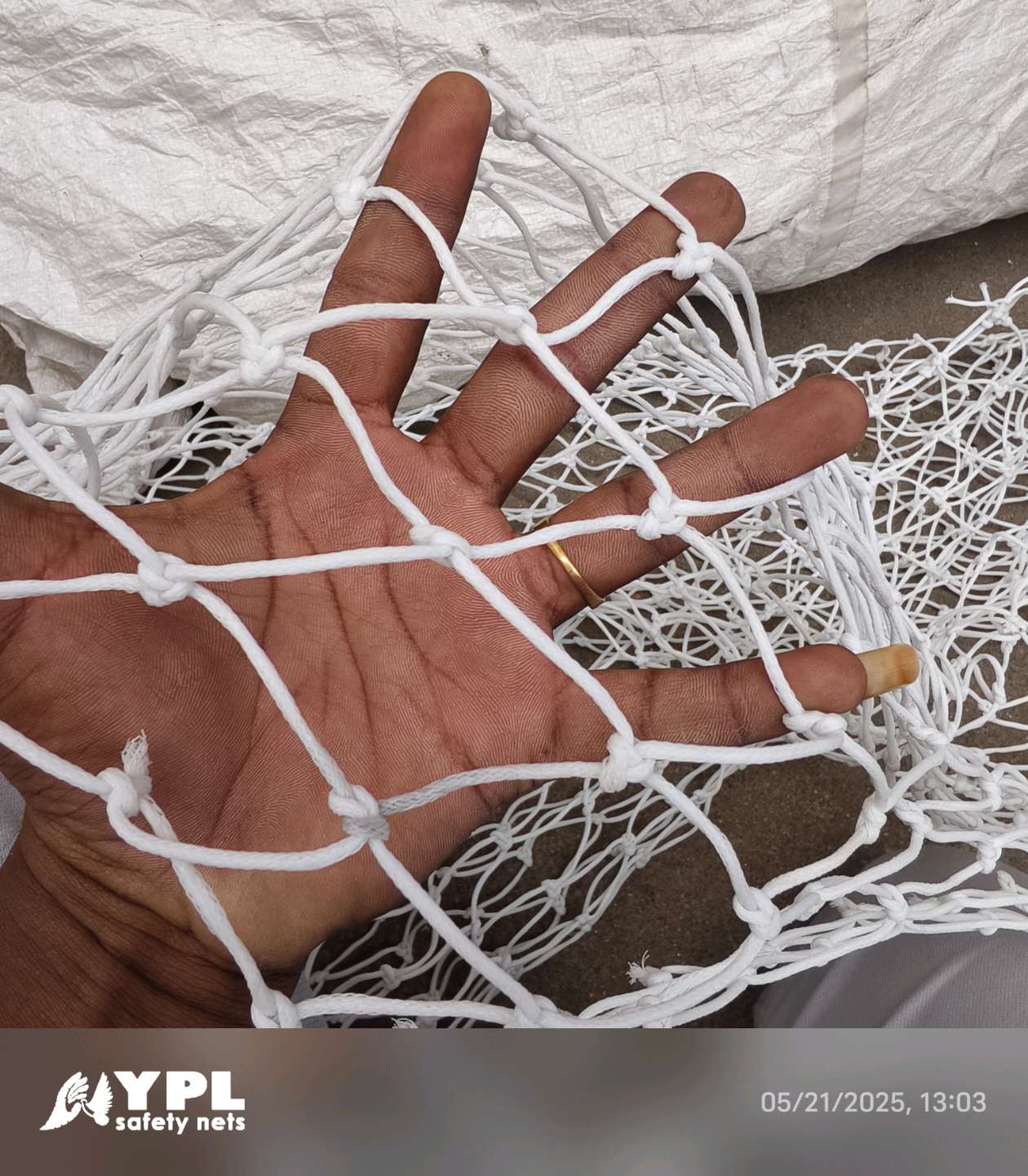 White knotted nylon safety net held in hand showing cord strength — YPL Safety Nets Chennai