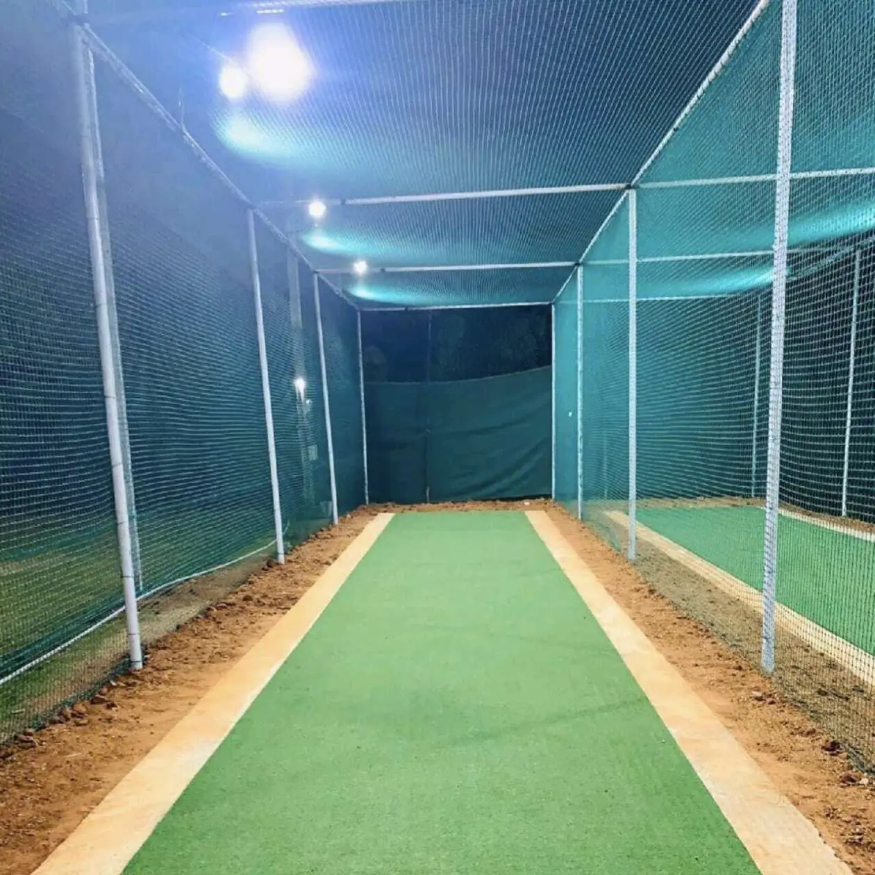 Floodlit cricket practice lane with astro turf and nets installed by YPL Safety Nets at night