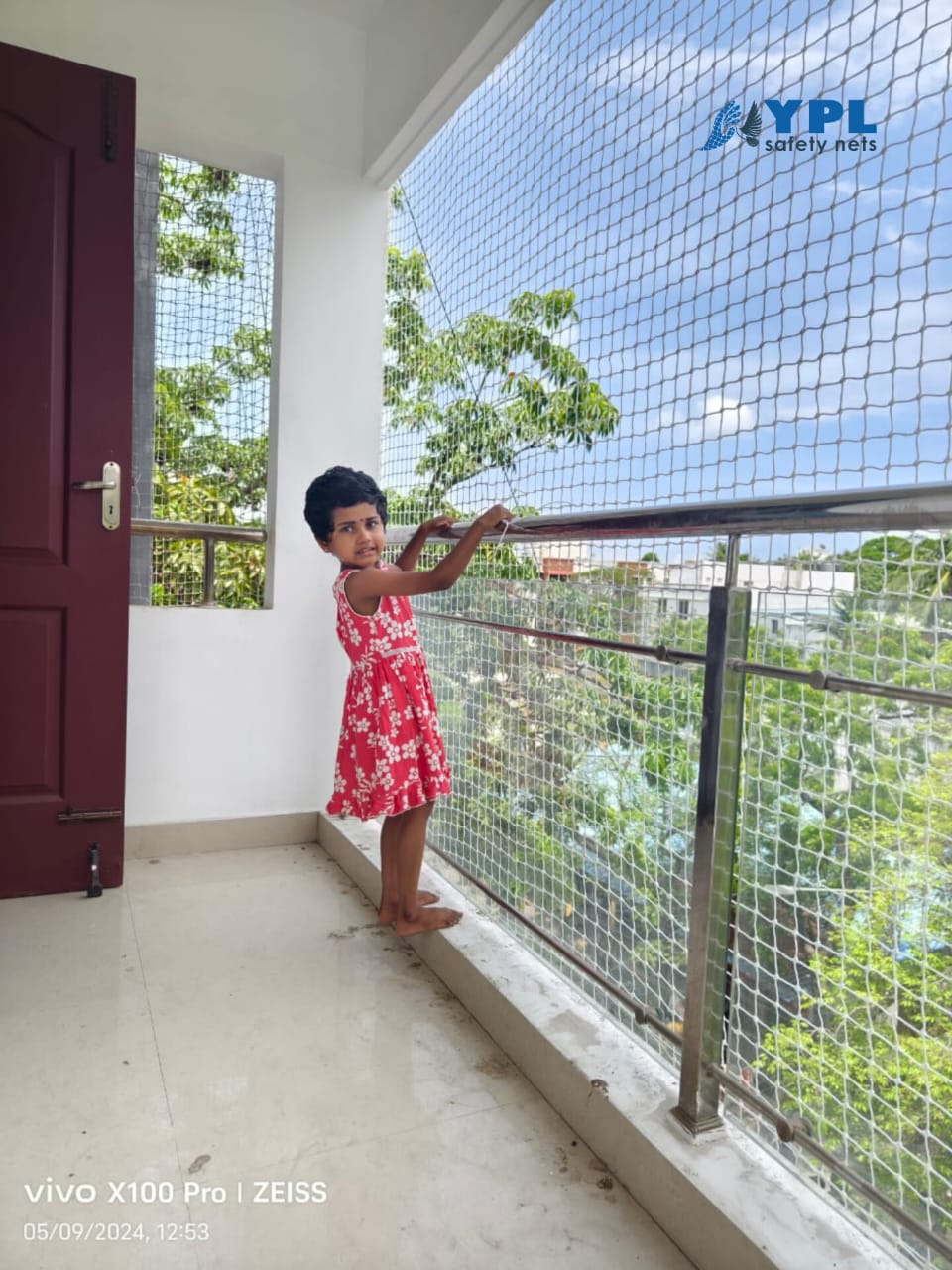 Child standing safely on an apartment balcony behind a children balcony safety net installed by YPL Safety Nets Chennai
