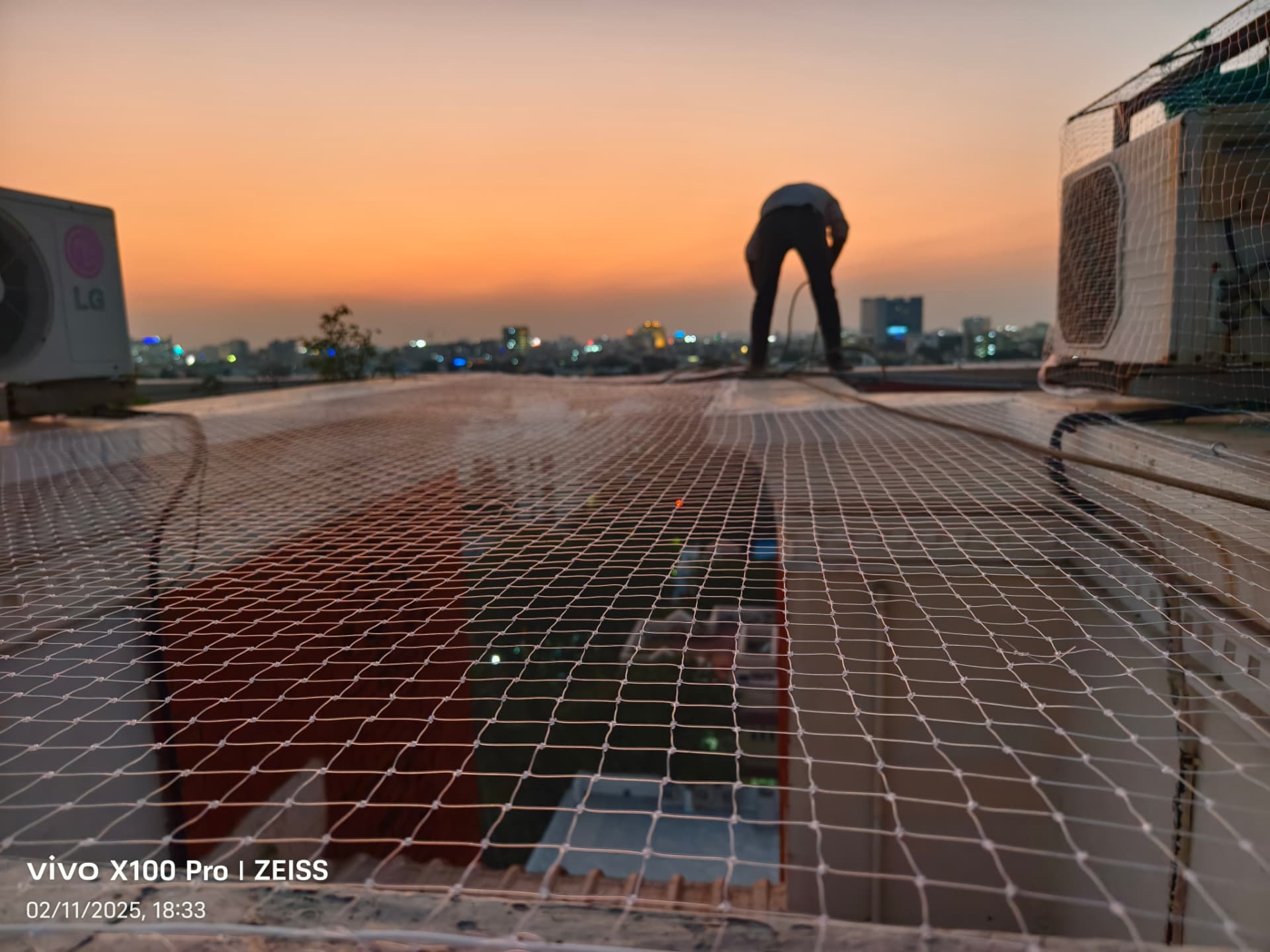 Technician installing a braided safety net on a terrace at sunset