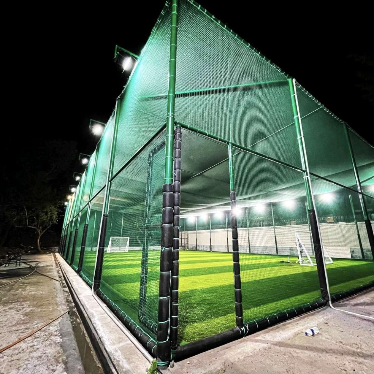 Floodlit box cricket turf enclosed with tall green turf nets installed by YPL Safety Nets