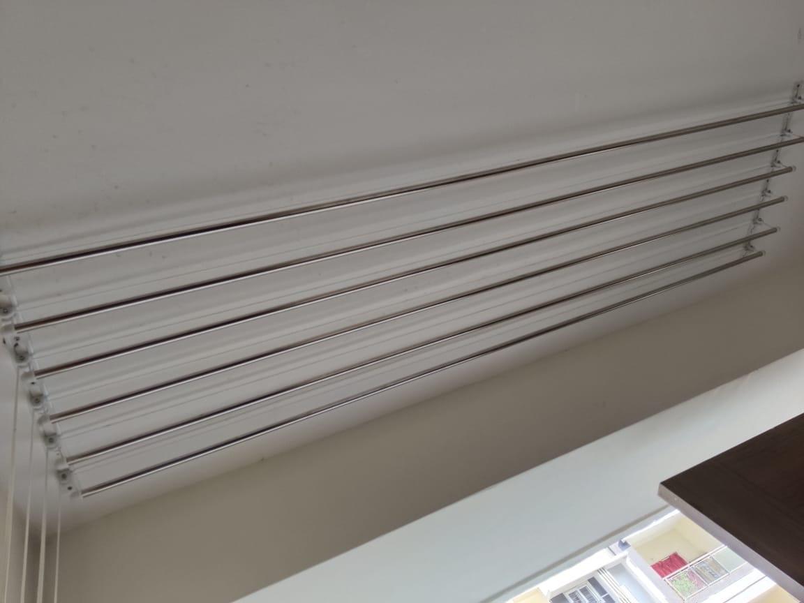 Eight-rod ceiling dryer installed above a bright apartment balcony