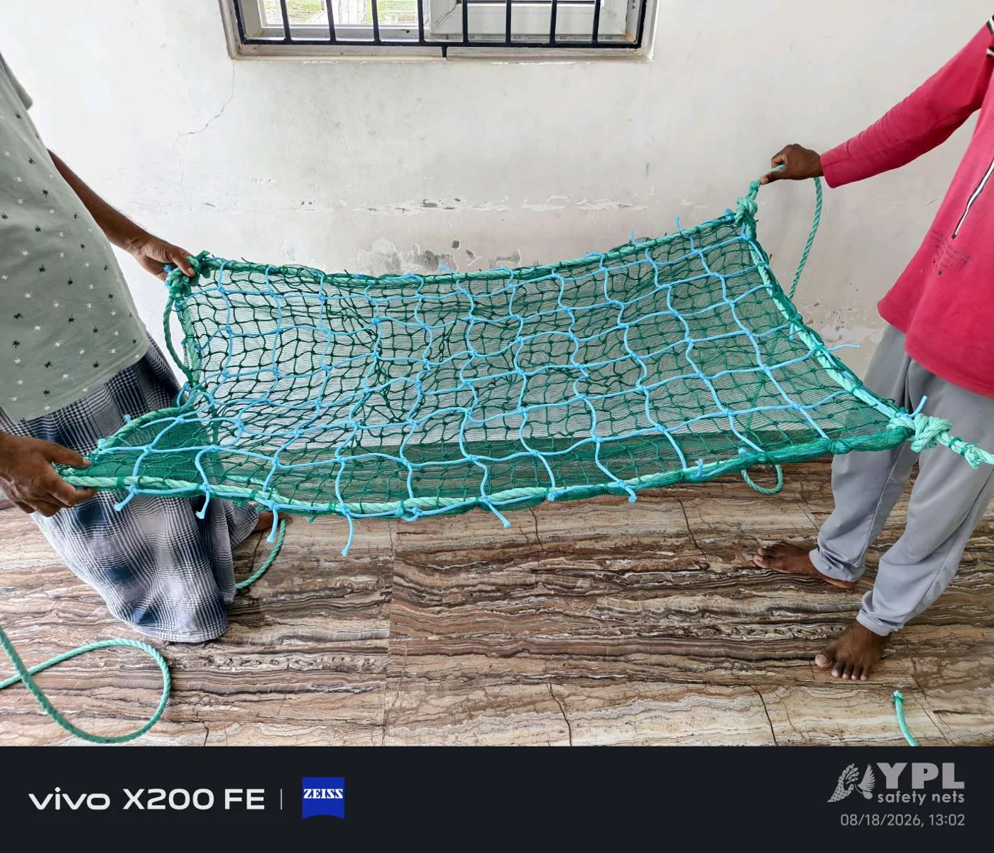 Double layer construction safety net panel with 2.5 mm braided net, 30 mm gap and PP rope border held open by YPL Safety Nets Chennai staff