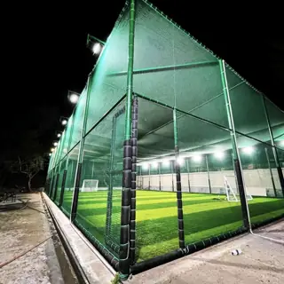 Floodlit box cricket turf enclosed with tall green turf nets installed by YPL Safety Nets